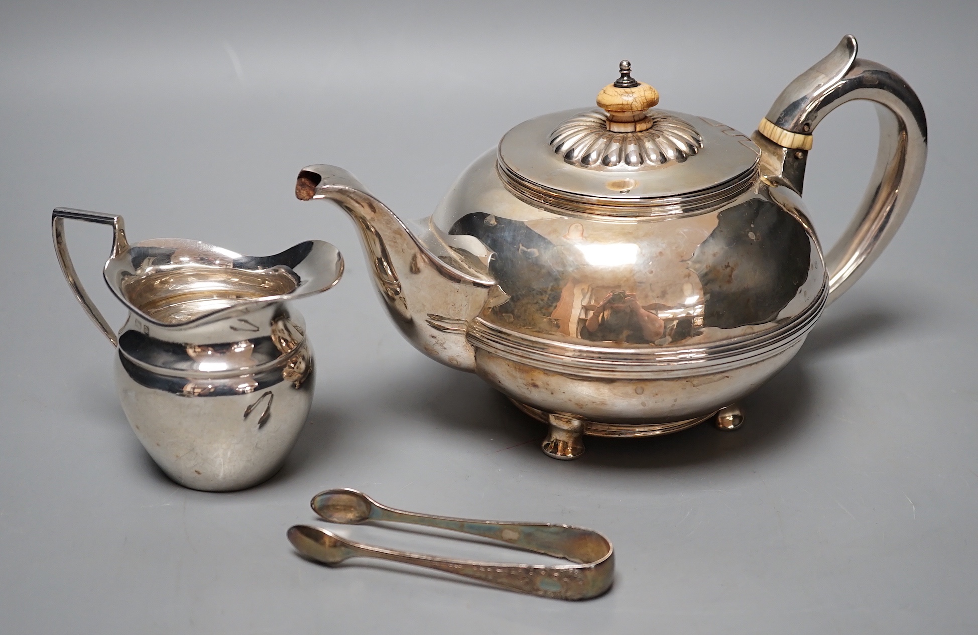 A George IV silver circular teapot, Craddock & Reid, London, 1824, a later silver cream jug and pair of silver sugar tongs, gross 19oz.